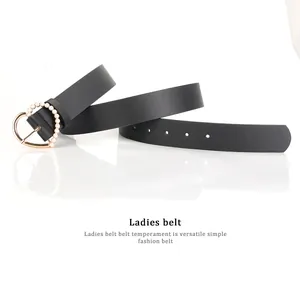 Detailed close-up of a black leather belt featuring a golden heart buckle with pearl inlay