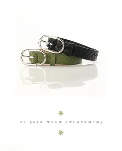 Detail of woven PU leather belts in black and olive green with silver oval buckles