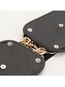 Macro shot of black textured leather belt with gold metal connector and silver rivets