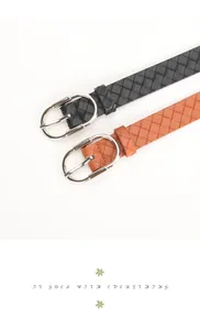 Close-up of woven PU leather belts in black and brown with polished oval silver buckles