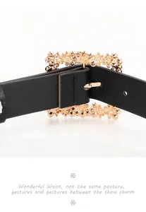 Detail of classic gold alloy buckle with intricate relief on a black slim leather belt