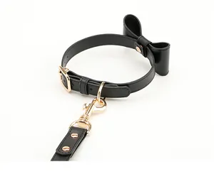 Detail of black PU leather pet collar and leash set with bowknot and golden hardware