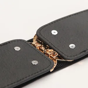 Elastic black waist belt featuring a stylish gold metal leaf buckle and leather accents
