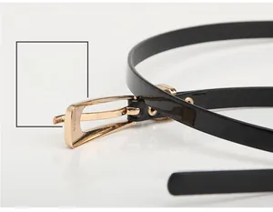 Détail d'une fine ceinture en cuir verni noir avec boucle dorée sur surface blanche lisse