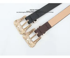 Close-up of vintage engraved gold buckles on black and brown slim leather belts