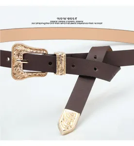 Close-up of vintage gold engraved buckle and metal tip on a dark brown leather belt