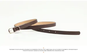Détail macro de la ceinture fine en similicuir marron avec boucle dorée ovale