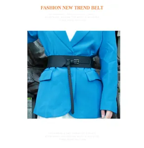 Detail of a wide black fashion waist belt with rectangular buckle styled on a blue blazer