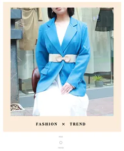 Detail view of a cream elastic wide waist belt with a gold round buckle on a blue blazer