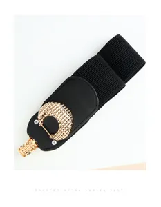 Detail of a wide elastic black belt featuring a vintage gold crescent buckle with texture