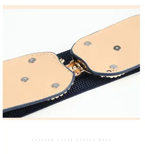 Detail of blue elastic wide belt with khaki leather patches and gold buckle closure
