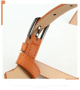 Detailed close-up of brown leather belt with metal buckle and fine stitching