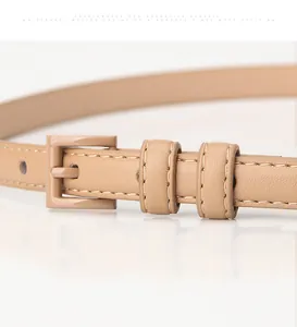 Dettaglio cintura sottile in pelle beige con fibbia quadrata e cuciture di precisione