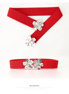 Détail d'une ceinture élastique rouge avec deux boucles en métal argenté en forme de fleurs