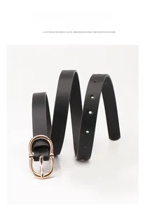 Detail of slim black leather belt featuring an oval gold buckle and adjustable holes