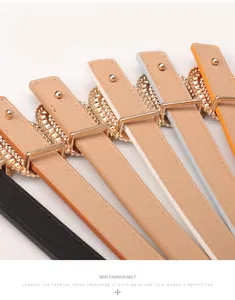 Close-up of thin leather belts in multiple colors with gold textured buckles