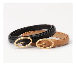 Dettaglio di cinture sottili da donna nei colori nero e cammello con fibbie ovali in oro