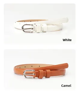 Dettaglio delle cinture sottili bianco e cammello con fibbie ovali argentate e passanti