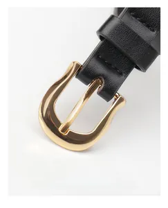 Detail of minimalist black slim belt featuring a polished gold U-shaped alloy buckle