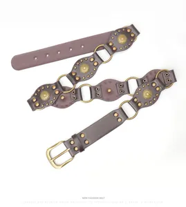 Detail of bohemian western belt with sunflower metal plates and brass rivets on brown leather