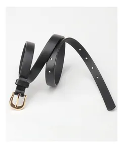 Detail of minimalist black leather skinny belt featuring a golden horseshoe buckle and holes
