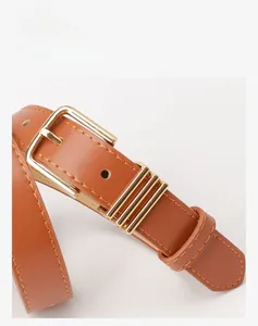 Détail d'une ceinture en similicuir marron avec boucle carrée en métal doré poli