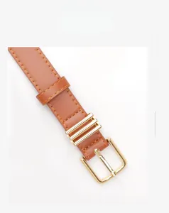 Détail de la ceinture marron en similicuir avec boucle dorée et passants métalliques polis