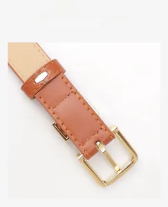 Détail d'une ceinture en cuir marron avec boucle dorée montrant l'attache arrière