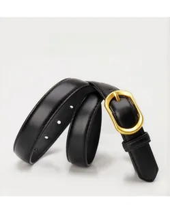 Détail d'une ceinture fine en cuir noir avec une boucle ovale en métal doré poli