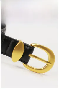 Detail shot of black leather belt featuring a matte gold alloy buckle and fine stitching