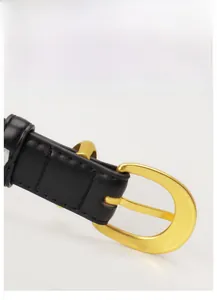 Detail of black faux crocodile leather belt featuring a polished gold solid alloy buckle