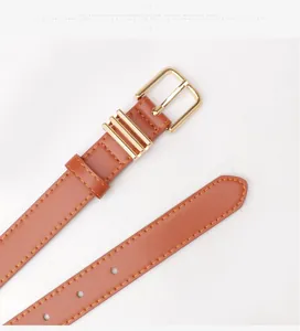 Détail d'une ceinture en similicuir marron avec boucle en métal doré et surpiqûres