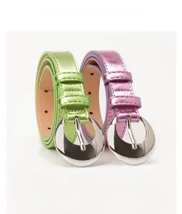 Detail of silver half-moon buckles on metallic green and pink glossy leather belts