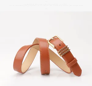 Détail de la ceinture en similicuir caramel avec boucle dorée et passants