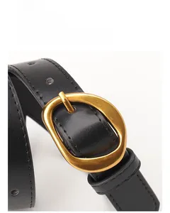 Detail of black leather belt with a polished gold oval buckle and fine stitching