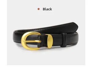 Detail of a minimalist black leather belt featuring a matte gold oval metal buckle