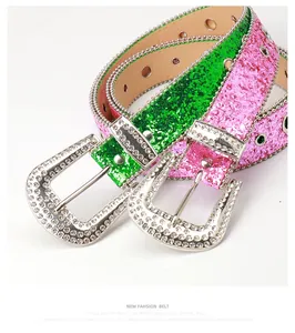 Detalle de cinturones brillantes en rosa y verde con hebillas de strass y ojales de metal