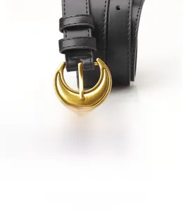 Close-up of black leather belt with golden crescent moon buckle and fine stitching