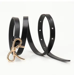 Detail of thin black leather belt with golden bow buckle and adjustable punch holes