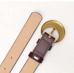 Detail of dark brown leather belt featuring a golden crescent buckle and stitched edges