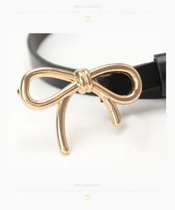 Detail of elegant black skinny belt with a polished gold bow buckle for women