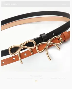 Close-up of black and brown leather belts featuring elegant golden bow metal buckles