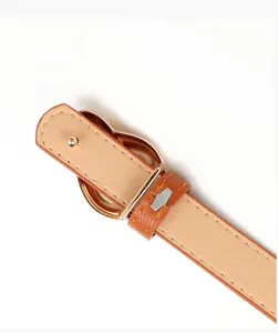 Detail of light brown leather belt back with polished gold buckle and fine stitching