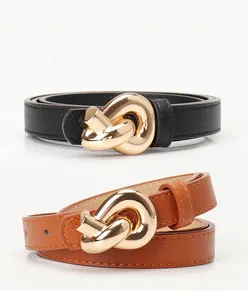Detail view of black and brown leather belts with elegant golden twisted metal buckles