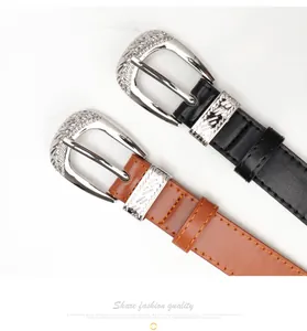 Detail of vintage carved metal buckles on black and brown belts with stitching