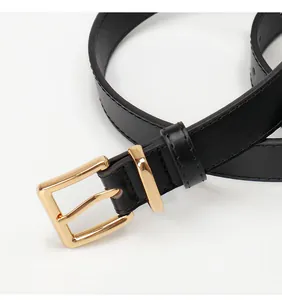 Detail of slim black leather belt featuring a polished gold square metal pin buckle