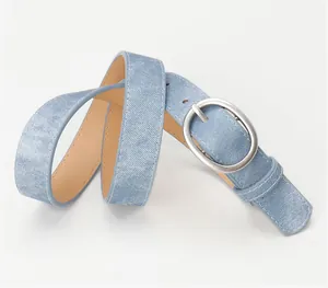 Macro detail of blue denim texture belt with silver oval buckle and smooth inner lining