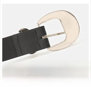 Detail of silver alloy crescent buckle on black leather belt with solid stitching