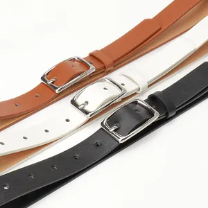 Three minimalist women's leather belts in black, brown, and white with silver pin buckles