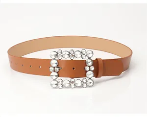 Detail of a brown leather belt featuring a large square buckle encrusted with rhinestones